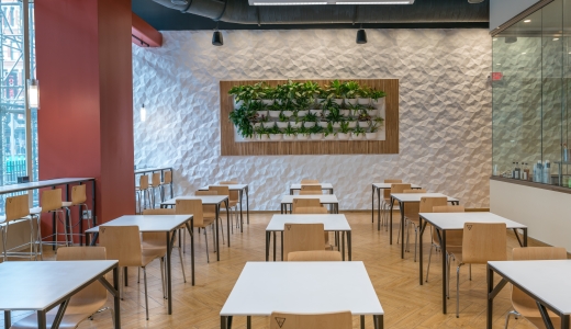Modern interior of Balance Grille Cleveland with minimalist decor, light wooden chairs, and square white dining tables.