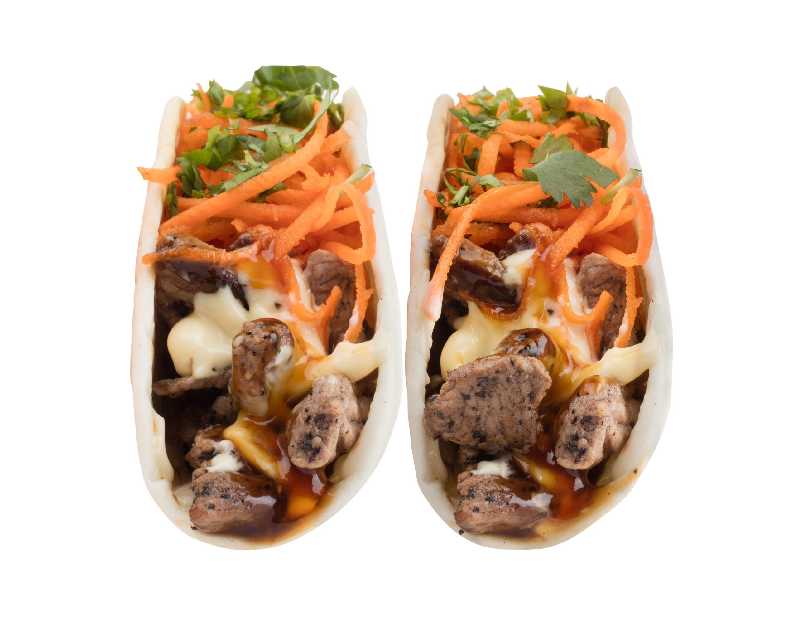 Two mongo tacos featuring wok-fired steak, shredded carrots, Balance Farms cilantro, Japanese mayo, and mongo sauce.
