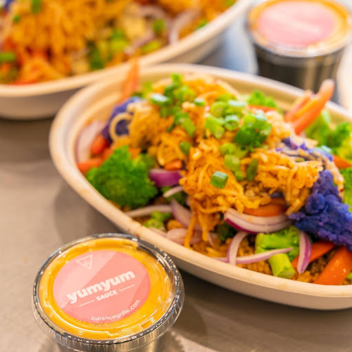 A fresh, aesthetically garnished Yum Yum Bowl with sauce at Perrysburg's Balance Grille.