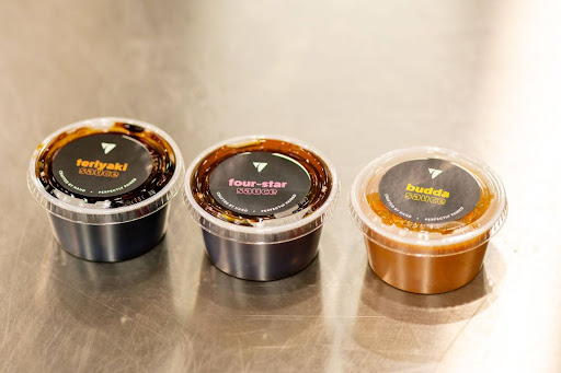 Three varieties of Balance Grille's sauces, including Teriyaki, Gochujang, and Fourstar, displayed on a table in Sylvania, Ohio.
