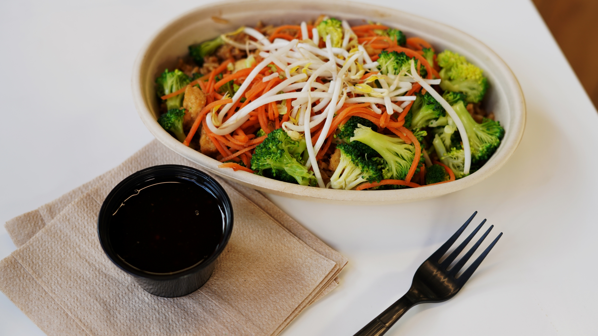 Customizable bowl loaded with tofu, broccoli, carrots, and sprouts, fast-casual never looked this vibrant.