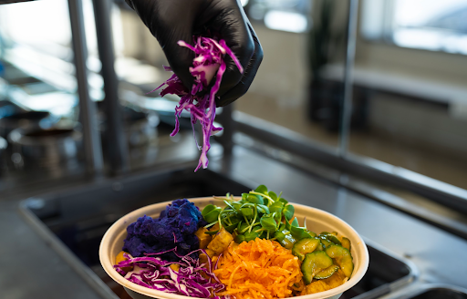 A chef at Balance Grille adds purple cabbage to a colorful bowl starring pickled cucumbers and root veggies.