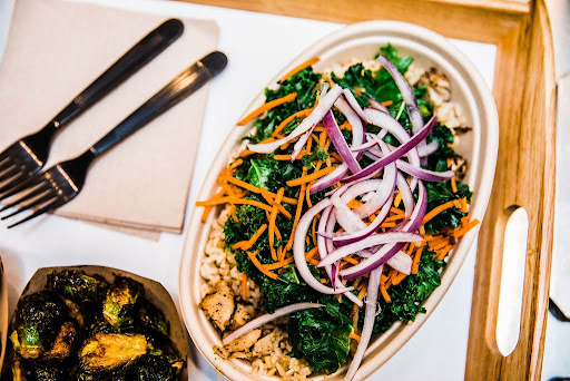 A vibrant grain bowl loaded with kale, carrots, and red onion is placed on a wooden tray at Balance Grille in Cleveland.