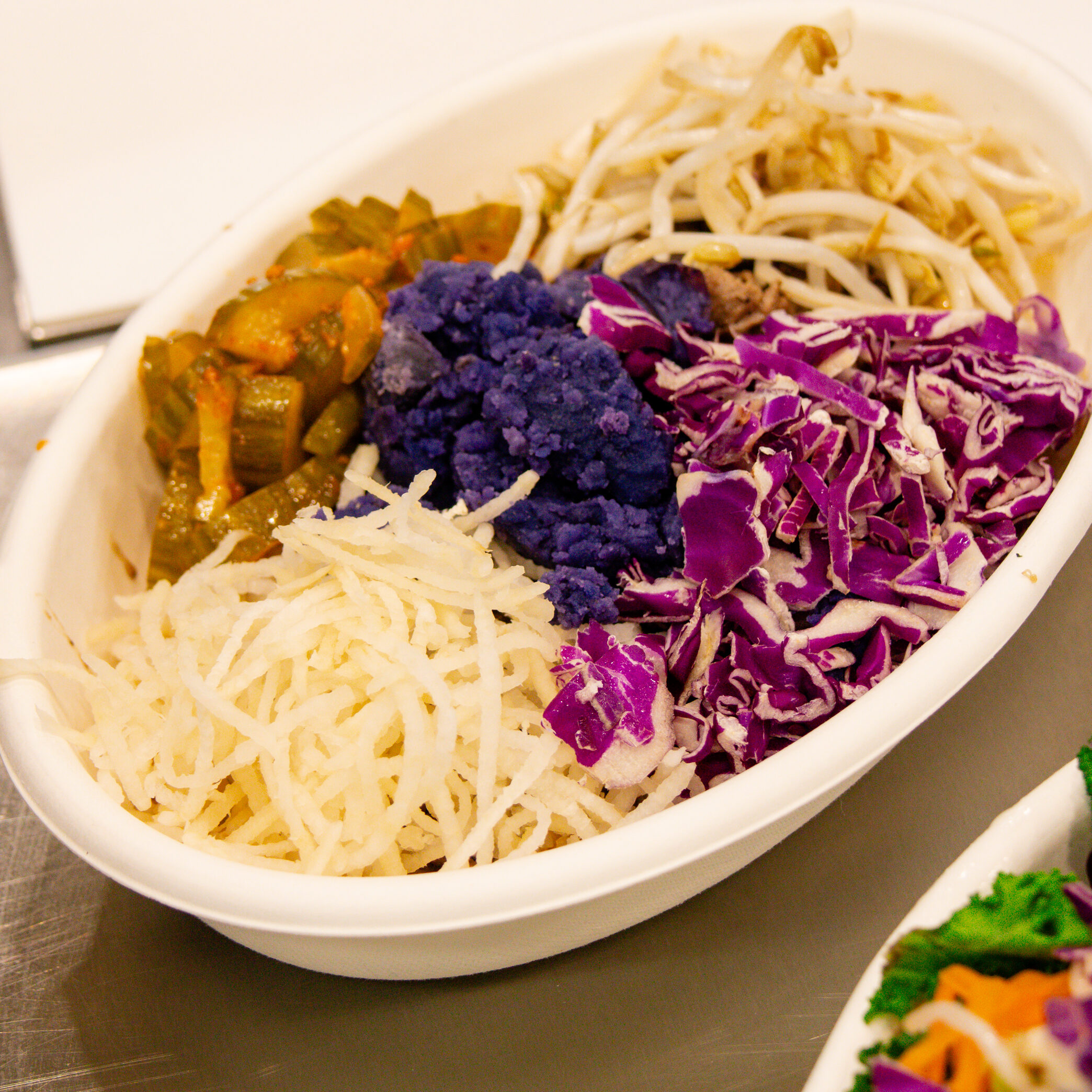 Korean Bibimbap bowl with grilled chicken, red cabbage, sprouts, daikon, and kimchi pickles.