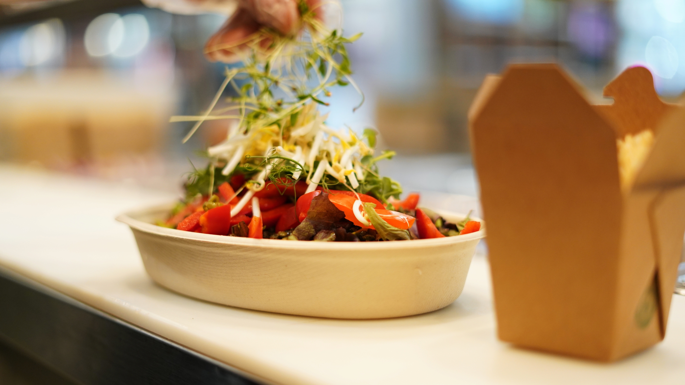 A close-up of a rice bowl from Balance Grille being garnished with a packet beside it.
