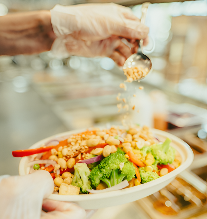 A staff member at Balance Grille is adding toppings to a protein-rich bowl. 