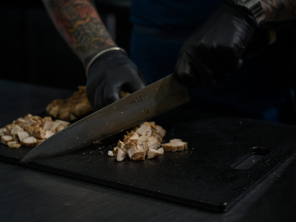 A chef at Balance Grille is cutting up the protein-rich chicken breast to add to a bowl.